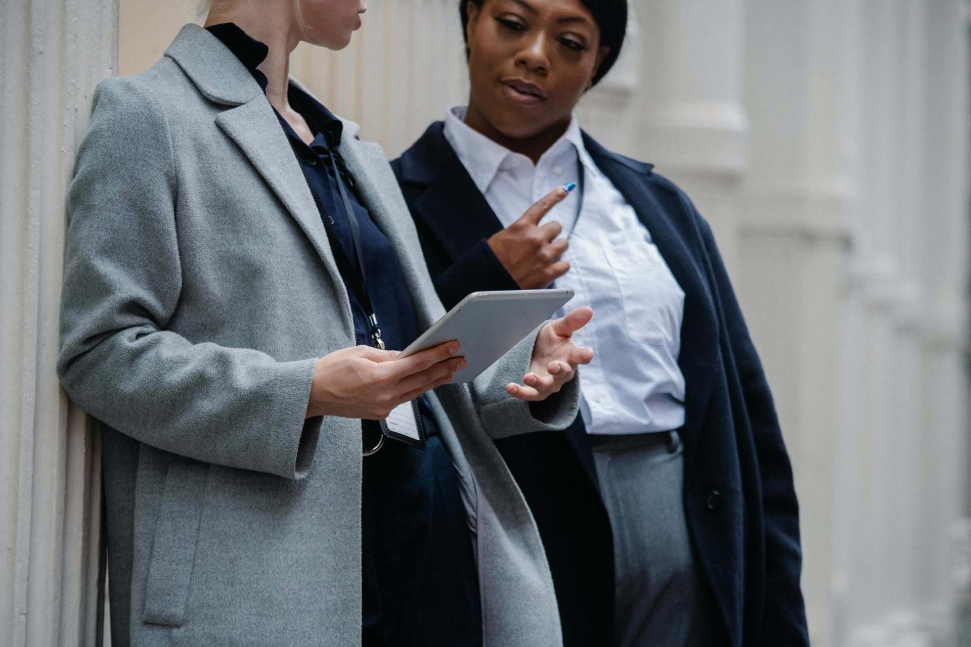 two women wearing id badges discussing information on a tablet