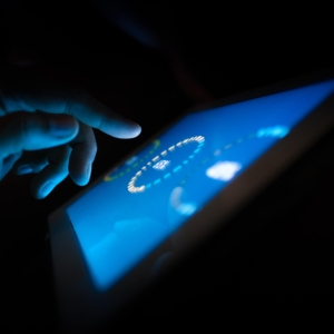 a hand tapping on a tablet in the dark