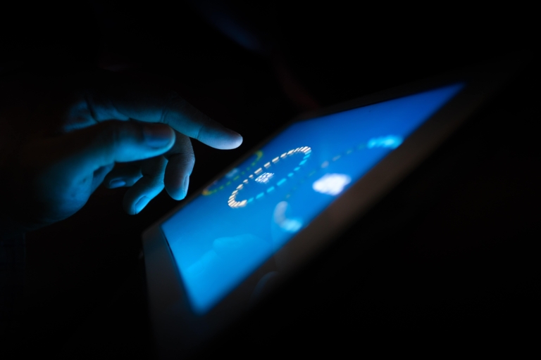 a hand tapping on a tablet in the dark