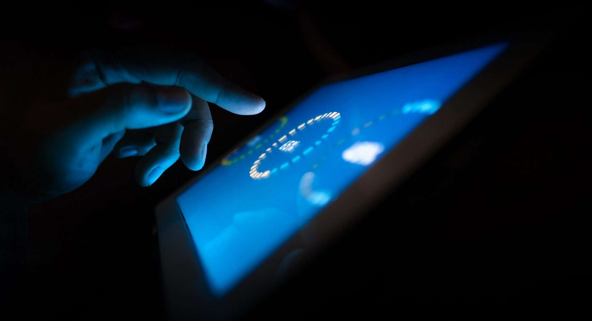 a hand tapping on a tablet in the dark