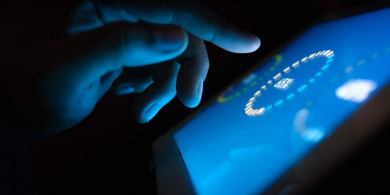 A hand tapping on a tablet in the dark