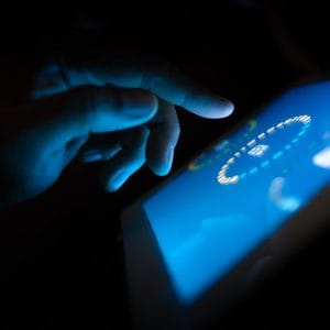 a hand tapping on a tablet in the dark
