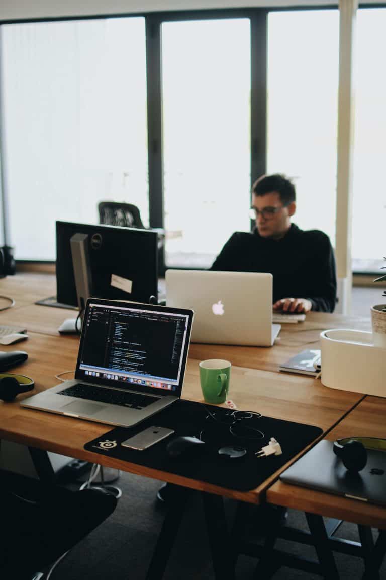 a man sitting at a desk with two laptops.