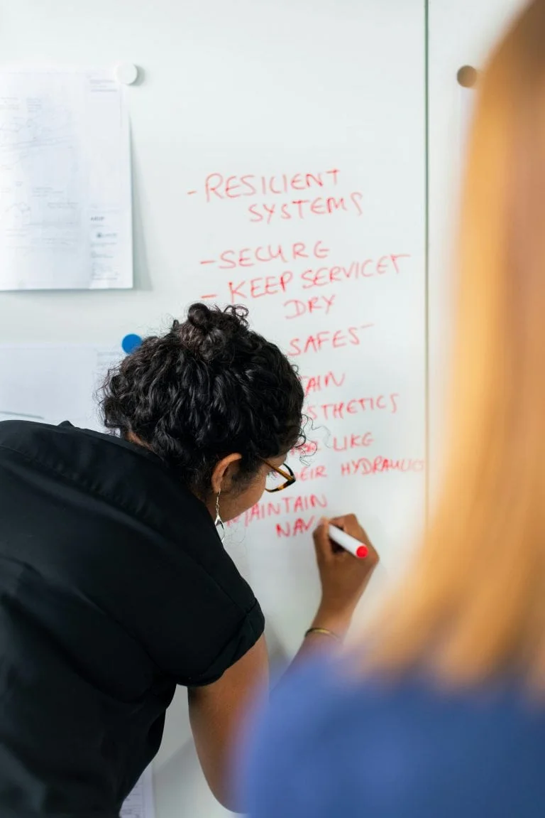 a woman writing on a whiteboard.