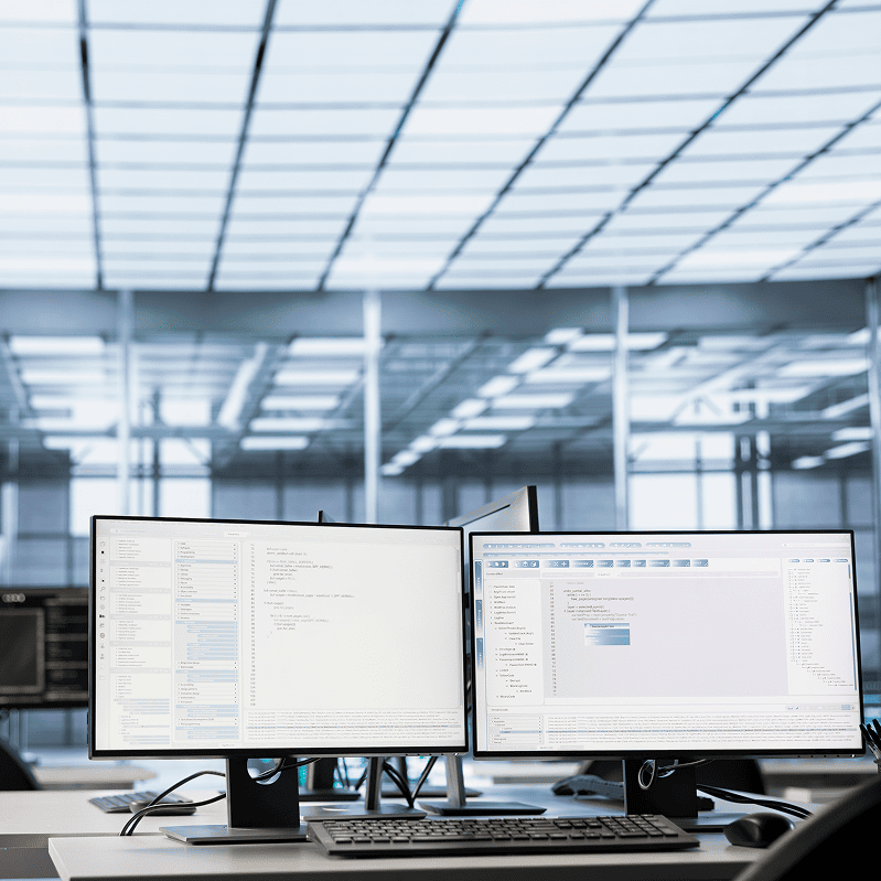 dual monitor workstation displaying code and development tools in modern office