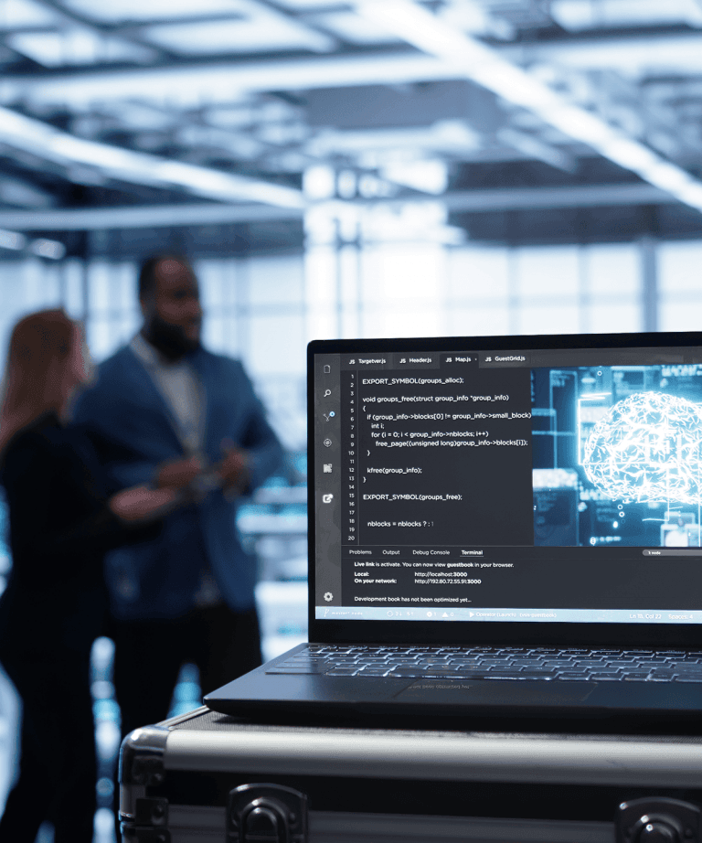 laptop displaying code and 3d visualization with professionals discussing in background