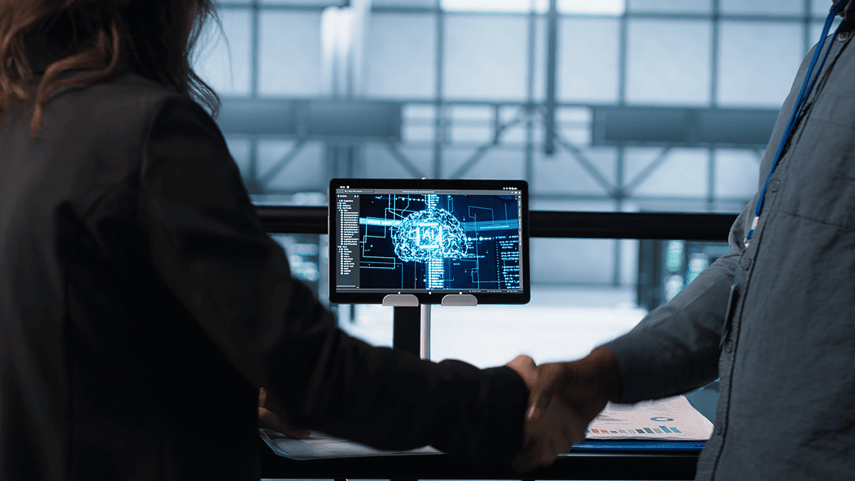 Two professionals analyzing artificial intelligence brain visualization on computer monitor in modern office