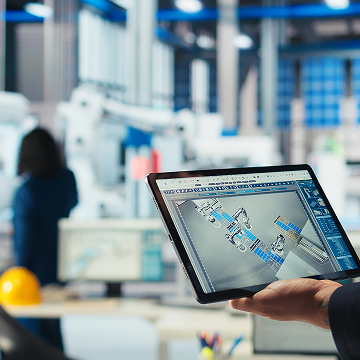 hand holding tablet displaying industrial facility schematic in manufacturing environment