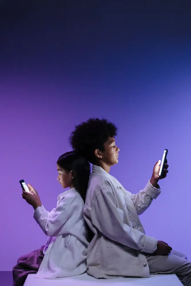 two people sit back-to-back, each looking at a lit phone against a purple gradient backdrop (tech use)