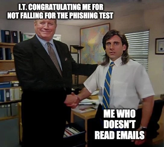 office scene with two men shaking hands in a cluttered desk area; top caption reads'I.T. CONGRATULATING ME FOR NOT FALLING FOR THE PHISHING TEST' and bottom caption reads 'ME WHO DOESN'T READ EMAILS'.